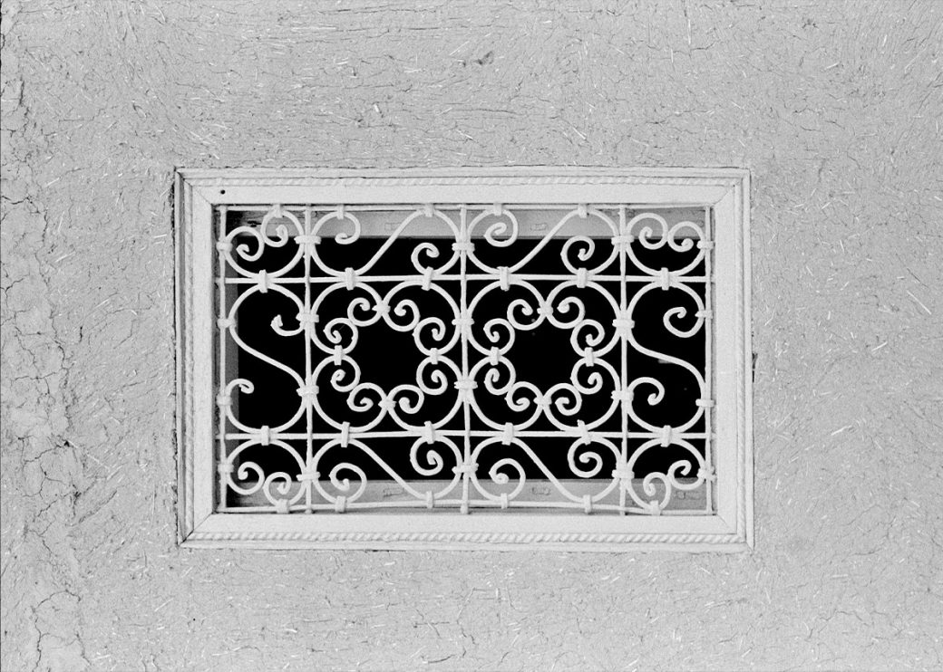 A rectangular metal window grate with swirled patterns.